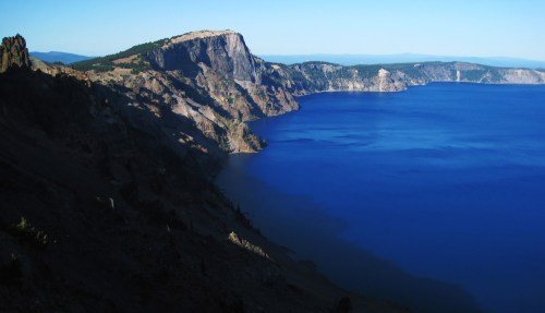 Crater Lake bathed blue calm cliff.  The jagged shadow of the rim cast by the setting sun was clearly visible on the unusually glassy surface of the lake.